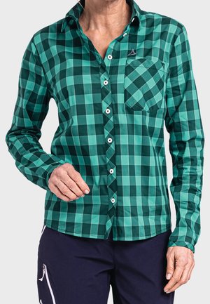 Camicia a maniche lunghe a quadri verdi con chiusura a bottoni, taschino sul lato sinistro e bottoni bianchi a contrasto; realizzata in tessuto liscio.