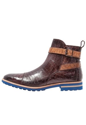 Bottine en cuir brun foncé à motif crocodile avec des sangles beige et une semelle en caoutchouc bleue, vue de profil.