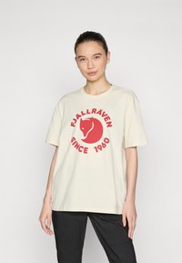 Tejhes, krém színű pamut póló, nagy piros róka grafikával és az "FJÄLLRÄVEN SINCE 1960" felirattal kör alakban. Rövid ujjú.
