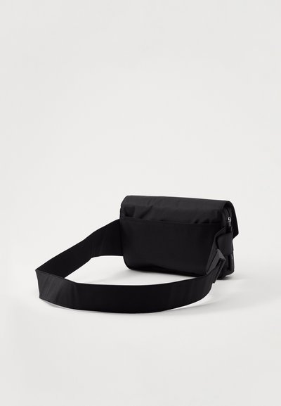 Mustast ristkülikukujulisest crossbody-kotist, mis on valmistatud vastupidavast kangast. Kott sisaldab eemaldatavat ja reguleeritavat rihma, samuti klappi, millel on lukuga tasku.