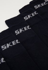 Jūras spēku zeķes ar teksturētu adījumu, kurās ir pelēks "SKEC" logos uz aproces. Dizains nodrošina ērtu piegulšanu ikdienas lietošanai.