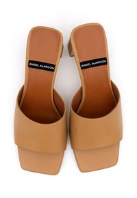 Sandali beige con tacco a blocco realizzati in pelle liscia, con una ampia fascia anteriore e apertura sul retro. Presentano un'etichetta nera con "ÁNGEL ALARCÓN."