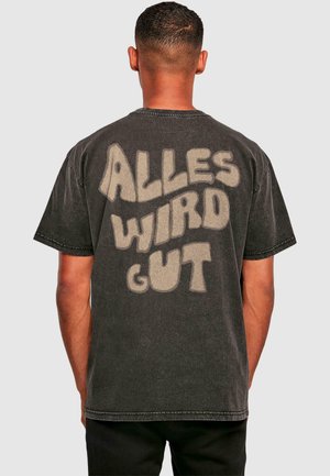 Sort bomulds t-shirt med stort, lyse teksttryk på ryggen, der står "ALLES WIRD GUT." Korte ærmer og løs pasform.