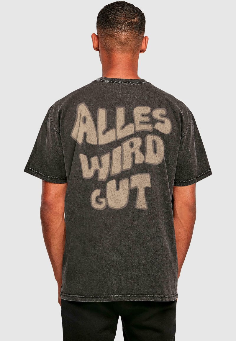 Sort bomulds t-shirt med stort, lyse teksttryk på ryggen, der står "ALLES WIRD GUT." Korte ærmer og løs pasform.