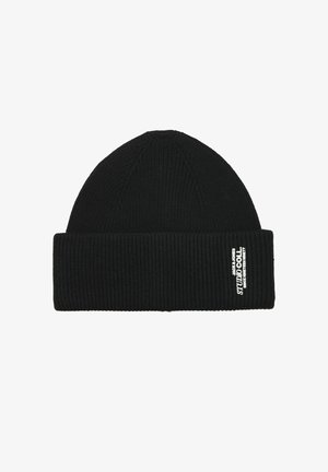 Gorro de punto negro con un puño acanalado doblado y una etiqueta de marca blanca en el lateral. La textura es suave y elástica.