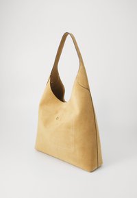 Suede handbag in light yellow, featuring a curved silhouette, a single wide strap, and a front pocket with minimalistic stitching detail.