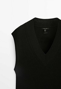 Schwarze ärmellose Strickweste mit tiefem V-Ausschnitt, die eine gerippte Textur und klare Linien präsentiert. Etikett im Kragen sichtbar.