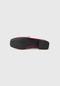 Sapata plana vermelha com parte superior lisa, bico arredondado e sola exterior de borracha preta durável com aderência texturizada. Design minimalista com um acento subtil.