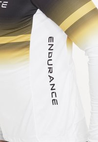 Langärmliges Sportoberteil in Schwarz, Gold und Weiß. Verlaufsmuster mit Mesh-Textur. Mit dem „ENDURANCE“-Logo in Bold an der Seite.