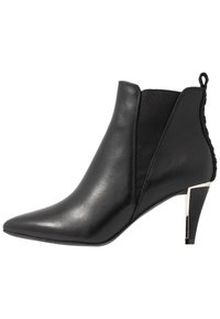 Svart läderankelboot med spetsig tå och elastiska sidopaneler. Har en silverfärgad klackaccent och en strukturerad dragflik bak.