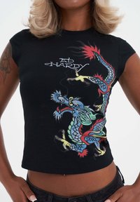 Černé zkrácené tričko s barevným grafikou draka a textem "Ed Hardy". Vyrobeno z měkké tkaniny, s krátkými rukávy a přiléhavým střihem.