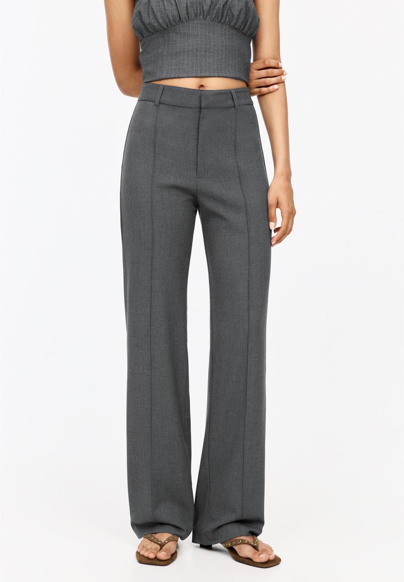 Pantalons larges gris en tissu texturé, arborant une taille haute et des coutures latérales pour un look ajusté, accompagnés d'un haut court.
