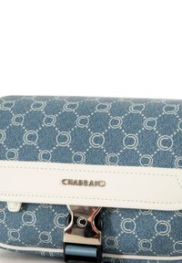 Blauwe denim tas met een wit cirkelpatroon, zilverkleurige hardware en een witte leren schouderband. De voorkant bevat het "CHABRAND" logo en een sluitingdetail.