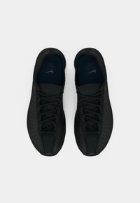 Pereche de adidași Nike Air negri cu un design perforat și șireturi, văzuți de sus pe un fundal alb.