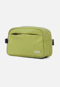 Kompakte, hellgrüne, rechteckige Kulturtafel mit Reißverschlusstasche auf der Vorderseite, schwarzen Seitenhandles und kleinem weißen Logo in der unteren rechten Ecke.