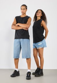 Črni brezrokavniki, ki jih nosita dva modela, v kombinaciji z usnjenimi hlačami in kavbojkami. Moški model nosi črne superge, ženski model pa črne gležnjarje.
