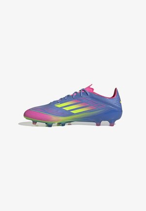 Chaussure de football futuriste bleue et rose avec des rayures jaune néon et une tige texturée, conçue pour jouer sur sol ferme.