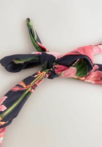 Sjaal met bloemenprint met een donkerblauwe achtergrond en roze en groene botanische ontwerpen; geknoopt in het midden, gladde textuur.