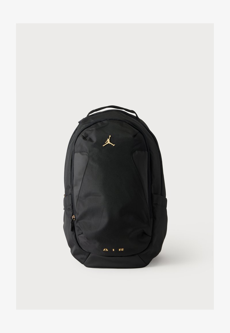Μαύρο σακίδιο πλάτης με χρυσλό λογότυπο Jumpman κοντά στην κορυφή και χρυσλό κείμενο "AIR" κοντά στο κάτω μέρος, με μπροστινή τσέπη με φερμουάρ και πλαϊνές θήκες.