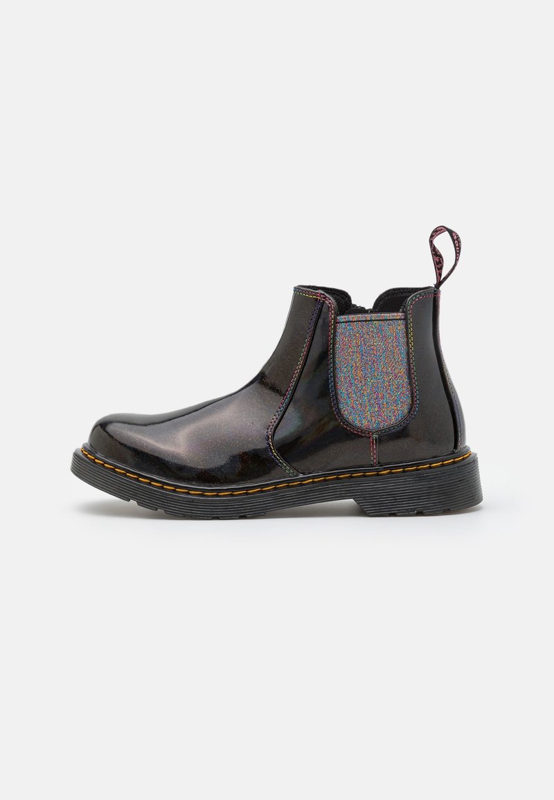 Botte Chelsea noire brillante avec panneau latéral élastique irisé, couture jaune sur la semelle et languette en tissu au talon sur fond blanc.