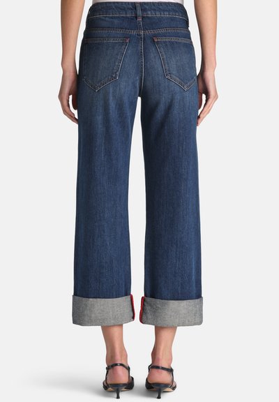 Tamnoplavene traperice širokih nogavica s preklopljenim manžetama u svijetlosivoj boji, s dvije stražnje džepove i suptilnim detaljima šavova.