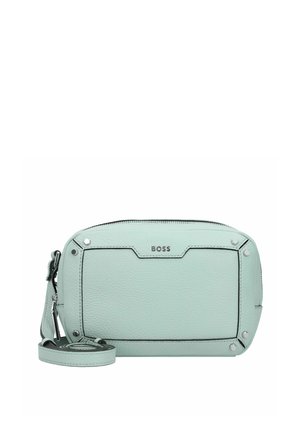 Hellmintgrüne BOSS Leder-Crossbody-Tasche mit Reißverschluss, Detail im vorderen Bereich und verstellbarem Gurt, der neben der Tasche zusammengerollt liegt.