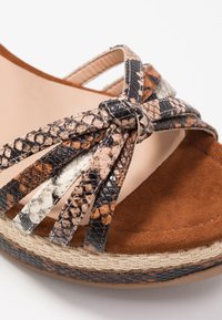 Sandalia de tacón alto con tiras de imitación de serpiente de colores, plantilla de ante marrón y suela de plataforma de yute trenzado. Detalle de lazo plano en las tiras.