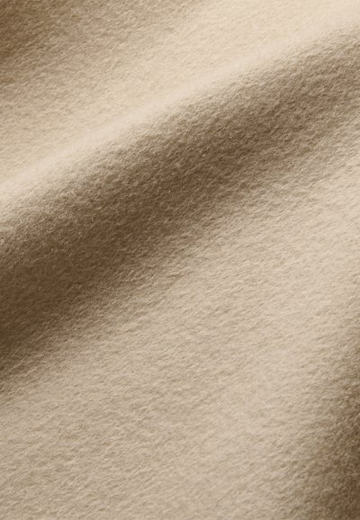 Felt di lana beige con una superficie morbida e testurizzata, che mostra sottili fibre e una caduta liscia e fluida.