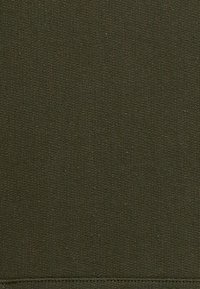 Σκουροπράσινος ύφασμα με υφή στην επιφάνεια, με ομοιόμορφη ύφανση και καθαρή, ακατέργαστη άκρη στο κάτω μέρος. Χωρίς σχέδια ή διακόσμηση.