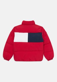 Giubbotto imbottito rosso con una toppa rettangolare bianca e blu navy nella parte superiore della schiena, con colletto alto e polsini elasticizzati.