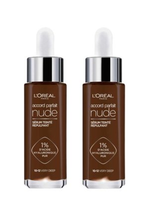 Deux flacons de sérum Accord Parfait Nude de L'Oréal Paris, présentant un élégant verre brun, des bouchons en argent et des étiquettes claires indiquant la teinte profonde et les ingrédients actifs.