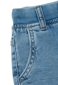 Pantalones de mezclilla azul claro con cinturilla elástica. Cuenta con un bolsillo lateral, costuras visibles y una textura suave.