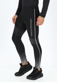 Zwarte leggings met een getailleerd ontwerp, voorzien van een vervagend stippenpatroon, een reflecterende zijkantstreep en een "SWEDEMOUNT" logo.