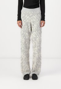 Fuzzy light gray and cream wide-leg pants with a textured pattern, featuring a gray elastic waistband. Worn with black shoes.