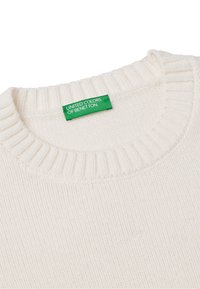 Biała swetrowa bluzka z okrągłym dekoltem. Zawiera zieloną metkę z napisem "UNITED COLORS OF BENETTON". Miękka tekstura, prosty design.