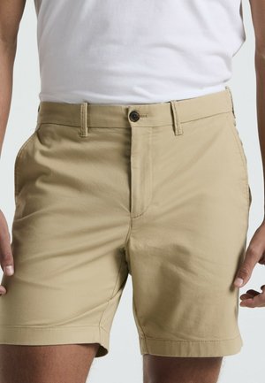 Beige shorts gemaakt van een katoenen mix, voorzien van een vlakke voorkant, knoopsluiting, riemlussen en zijzakken.