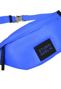 Riñonera de nylon azul con un diseño elegante, que presenta un parche de logo negro con la inscripción "STUDIO BERLIN" y una hebilla de metal plateada.