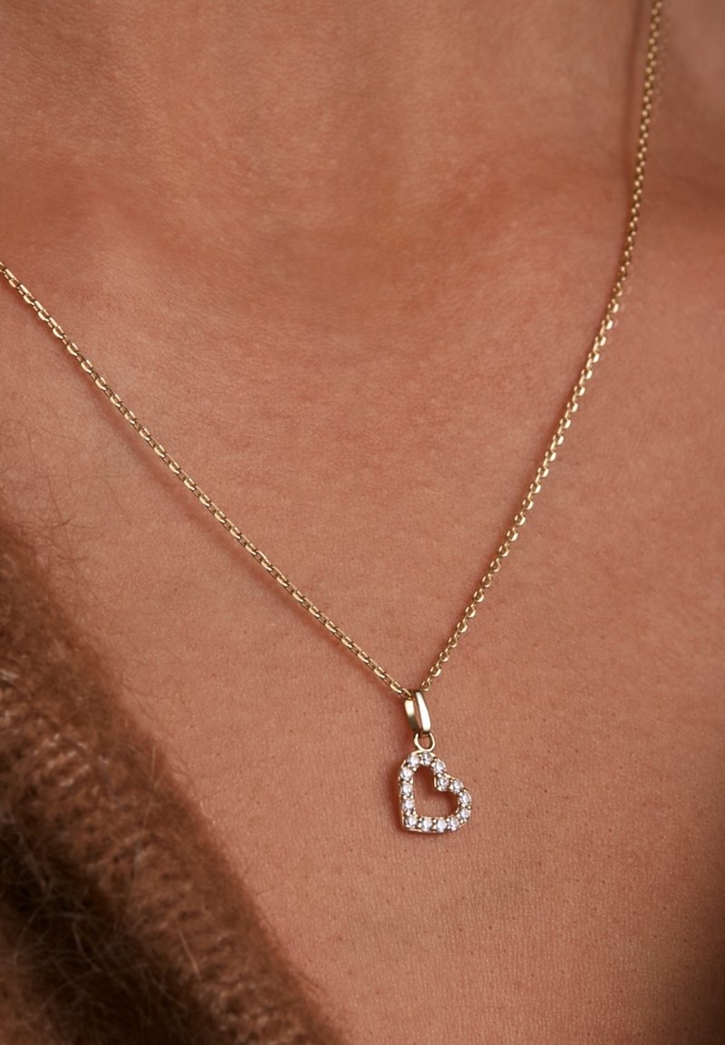 Collier en or avec un pendentif en forme de cœur orné de pierres claires, monté dans un cadre texturé.