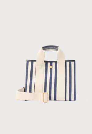 Sac cabas en toile couleur crème à rayures verticales bleu marine, avec de larges anses, une bandoulière amovible et une boucle dorée.