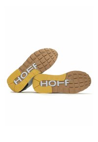 Zapatillas de deporte grises y negras con una suela de goma marrón. Presentan un distintivo acento amarillo y la marca "HOFF" en blanco en la suela. Patrón de banda de rodadura texturizado.