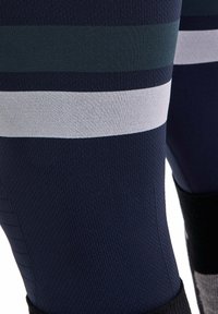 Marineblauwe sportlegging met textuur, horizontale strepen in donkergroen en grijs, en een contrasterende zwarte tailleband.