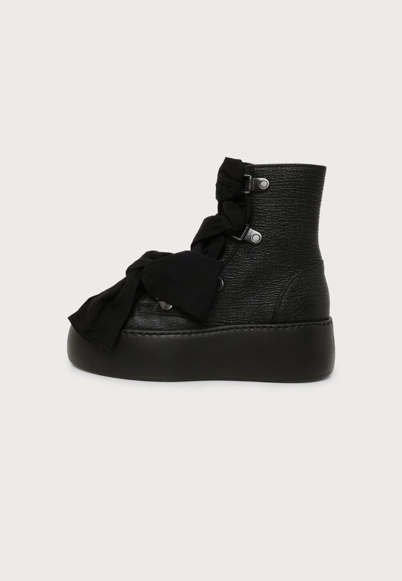 Bottine noire texturée à plateforme avec une semelle épaisse et un grand nœud en tissu noué sur la zone des lacets avant.
