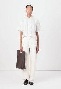 White striped short-sleeve shirt, cream wide-leg pants, black shoes, and a brown tote bag with a minimalist design. Smooth textures throughout.