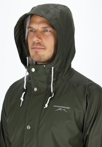 Olijfgroene waterdichte jas met een capuchon, verstelbare trekkoorden, drukknopen en een logo op de borst. De textuur ziet er glad en glanzend uit.