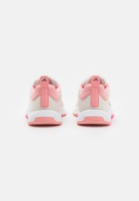 Footwear with a white upper, pink accents, and a ridged white sole. Features a prominent pink heel tab labeled "TRAINING."
