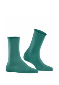 Chaussettes de cheville vertes en tissu lisse, avec un design ajusté et des bords côtelés. Conviennent pour un usage décontracté ou sportif.