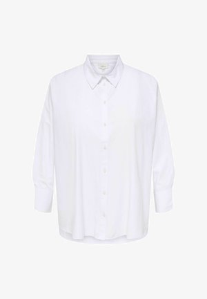 Chemise blanche à manches longues avec col pointu, coupe ample et design simple, présentée sur un fond uni.