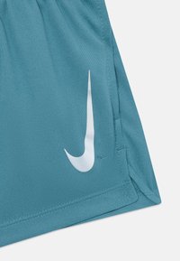 Shorts de sport teal avec une texture lisse, comportant un logo Nike blanc sur le côté et des panneaux en maille subtils pour la ventilation.