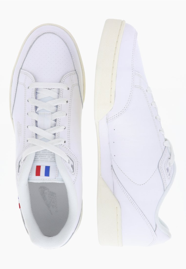 Weiße Sneaker mit einem perforierten Design, flachen Schnürsenkeln und einer kontrastierenden beige Sole. Besitzt ein kleines französisches Flaggen-Element nahe der Zunge.