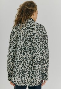 Leopardprint skjorte i lys beige med mørke pletter, med krave, knaplukninger og lange ærmer. Blød tekstur, afslappet pasform.